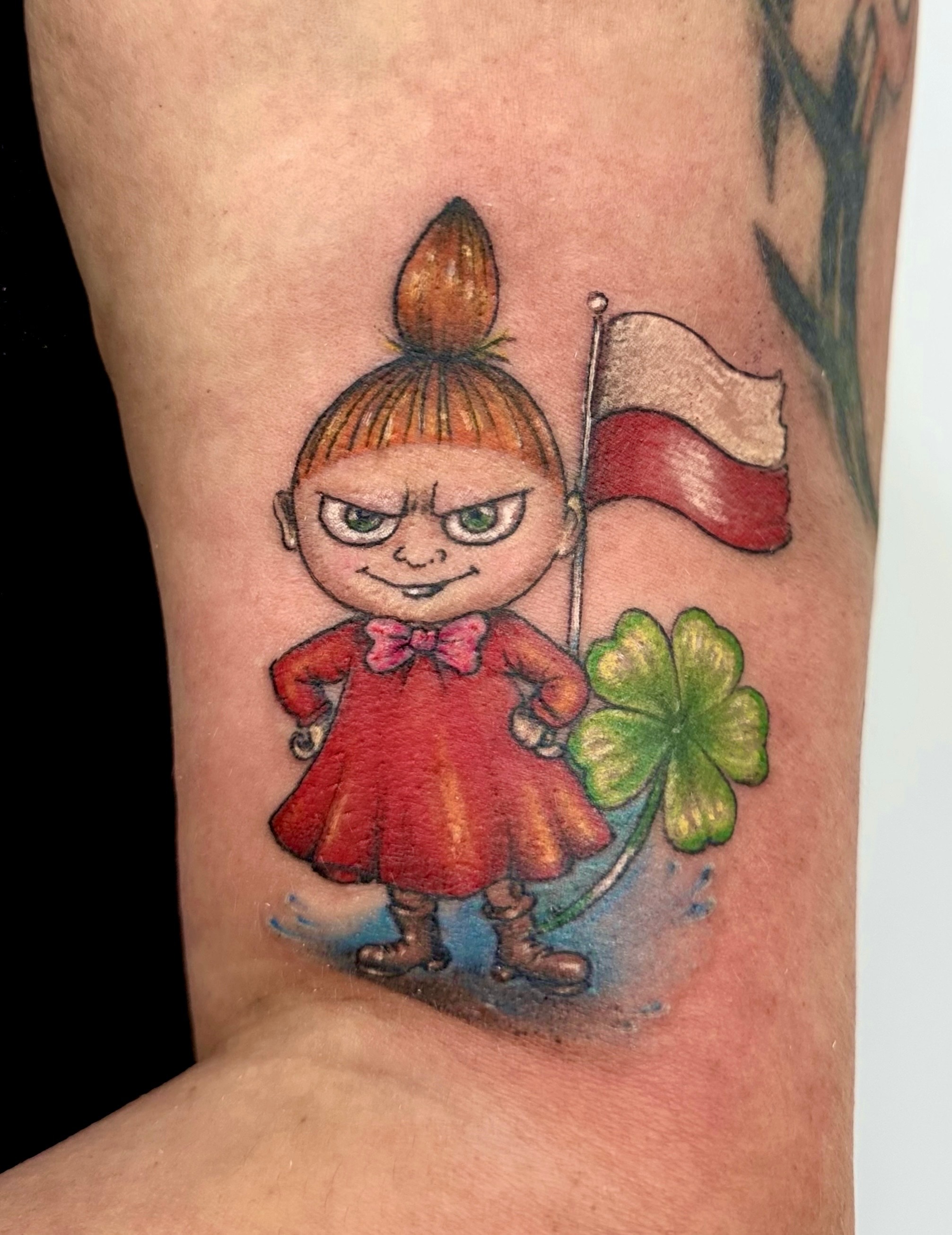 Colour cartoon tattoo of a girl in a red dress holding a Polish flag beside a four leaf clover