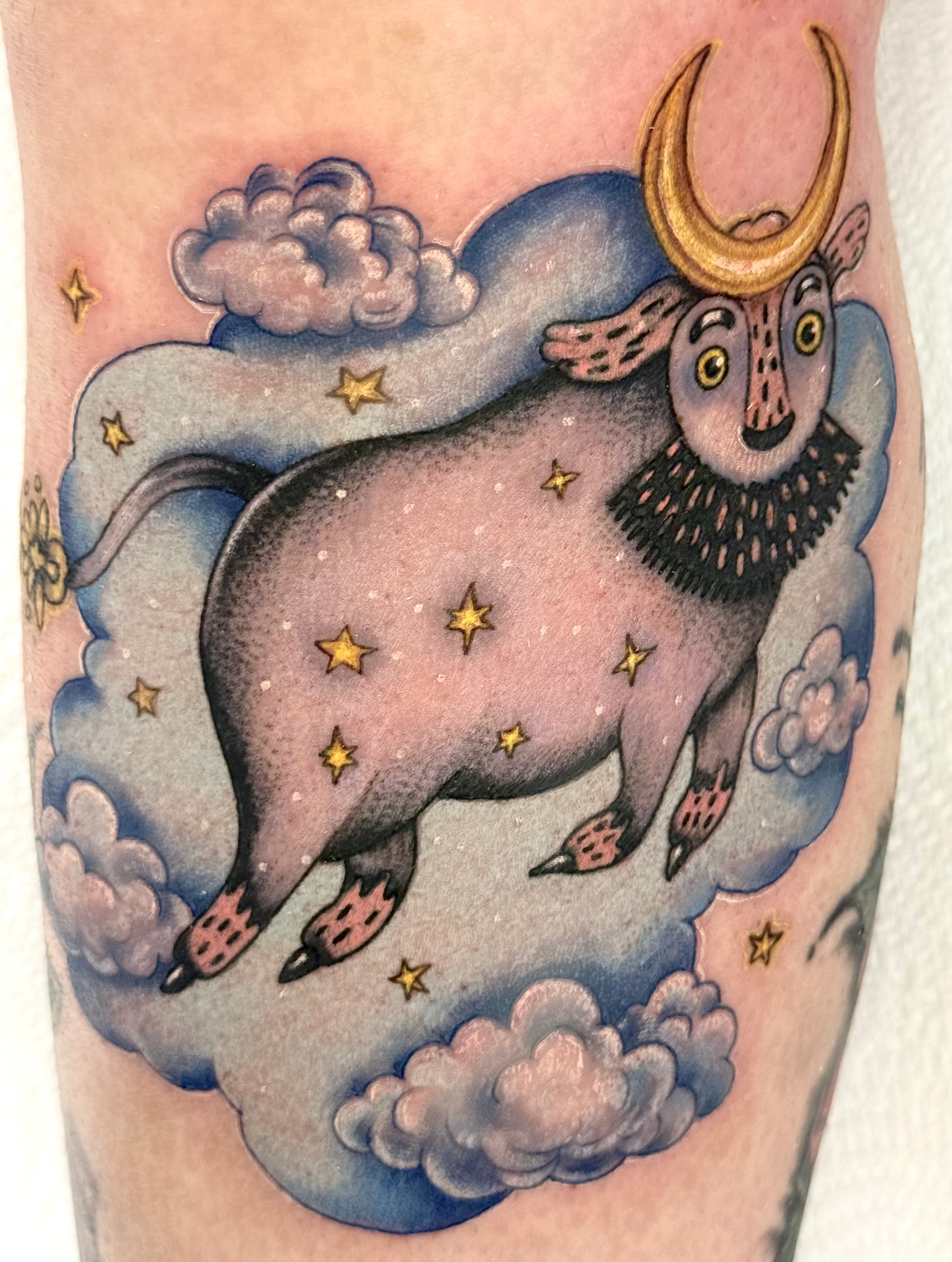 Colour tattoo of a bull with crescent moon horns, yellow stars and blue clouds