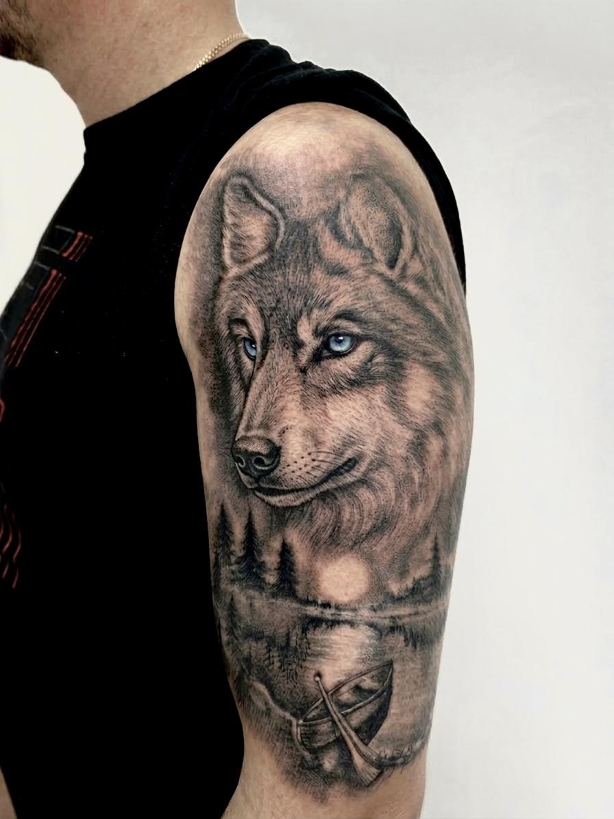 Black and grey wolf and lake scene tattoo with blue eyes on the shoulder.