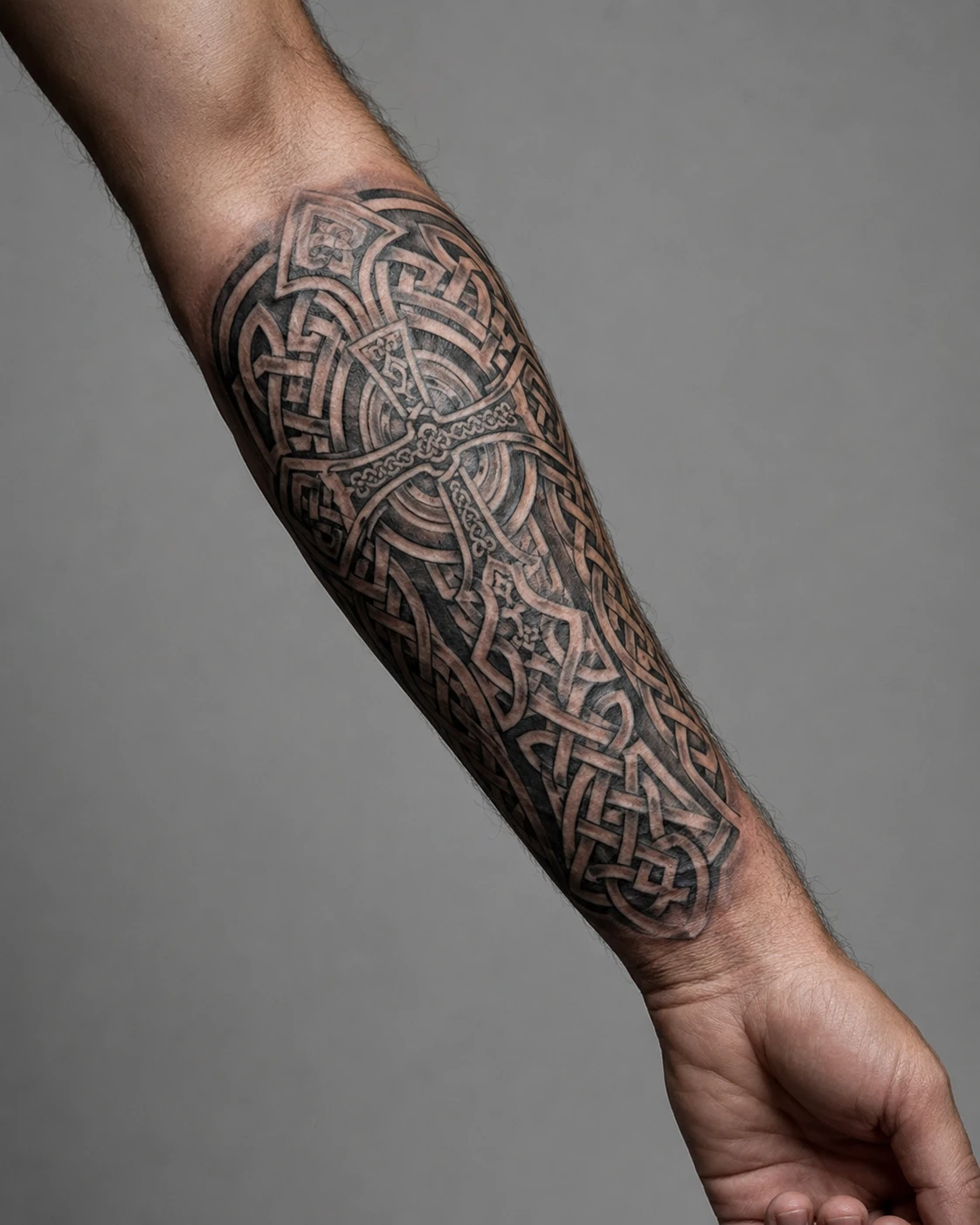 Interlaced Celtic knotwork around a ringed cross covering the forearm to the wrist