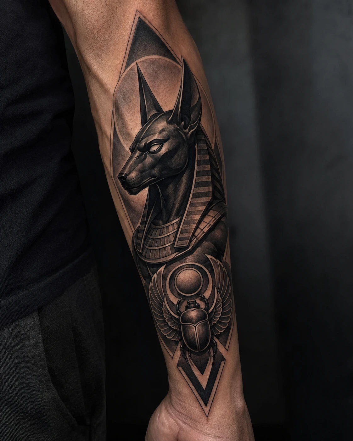 Anubis profile above a winged scarab and geometric sun disc.