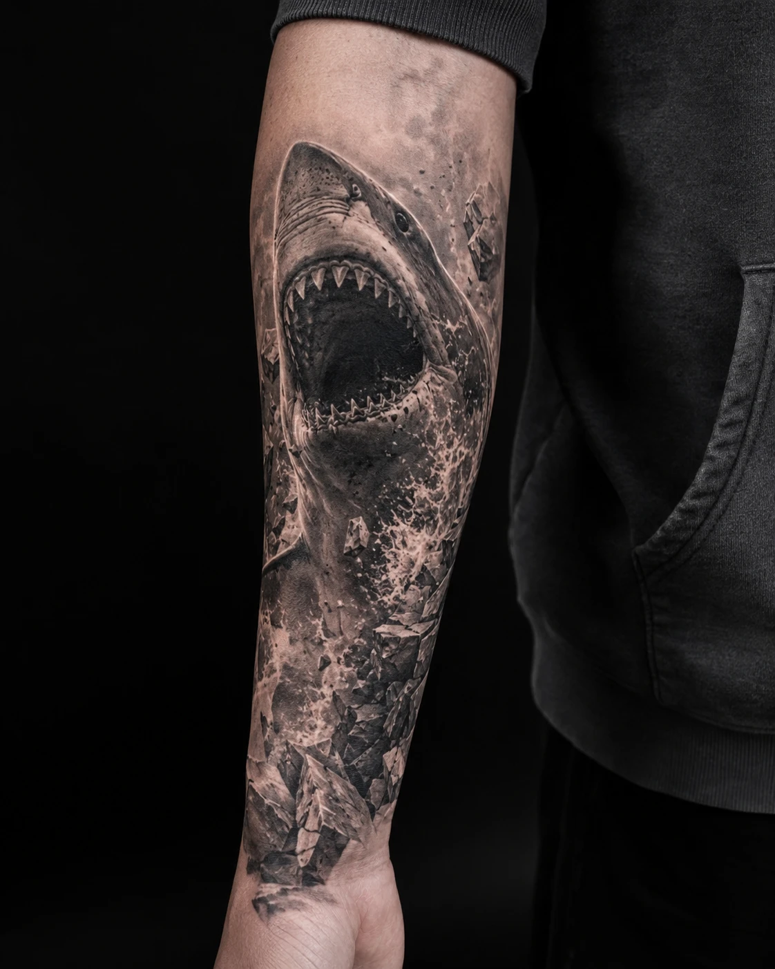 Great white shark turns through dark water with open jaws, textured skin and drifting bubbles.