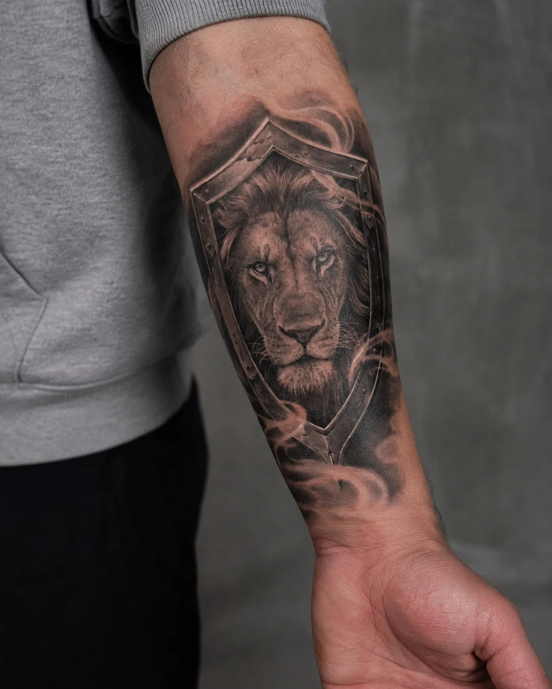 Lion portrait framed by classical stone arch tattoo on forearm