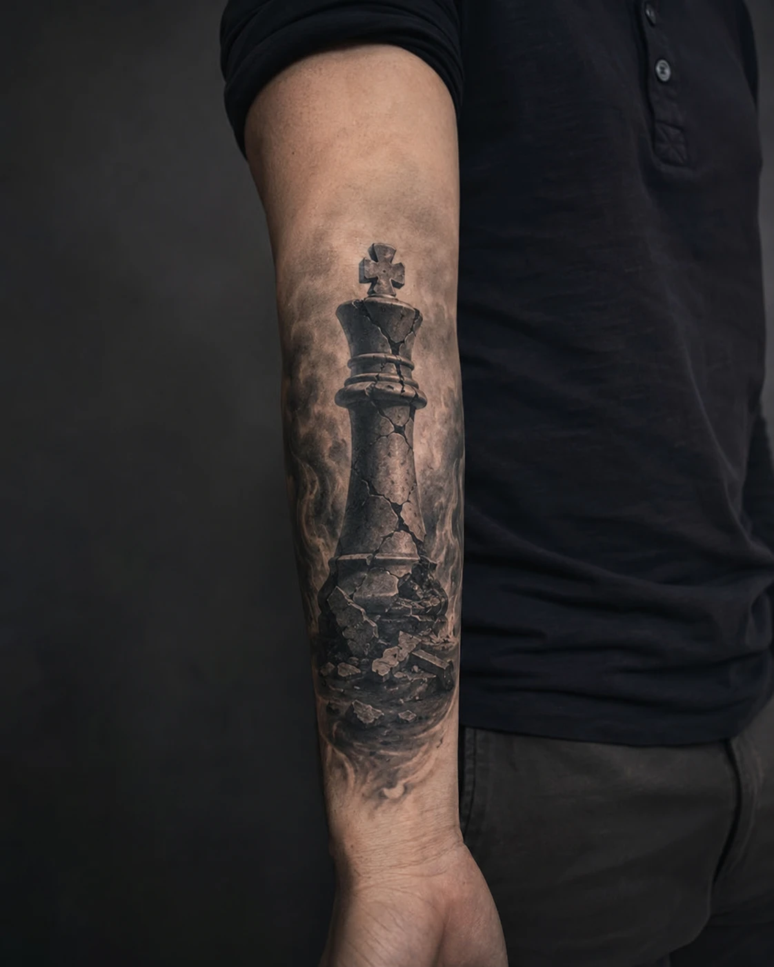 Ruined stone chess king on a shattered plinth tattooed on the forearm