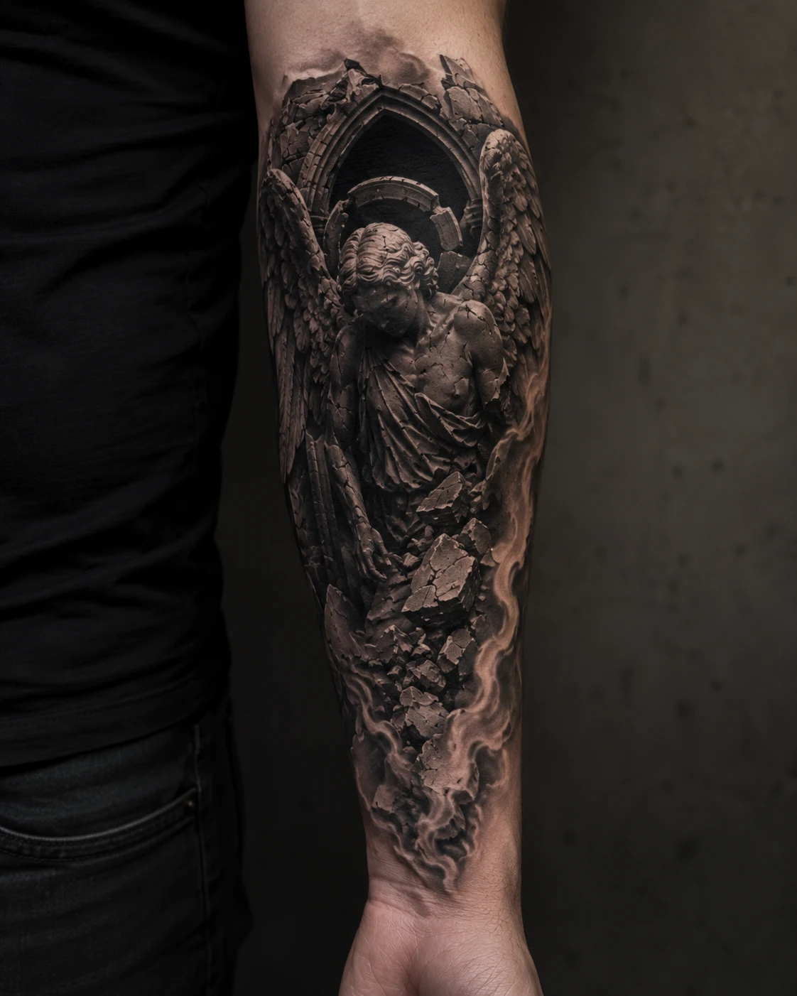 Weathered stone angel beneath Gothic arch tattoo on forearm