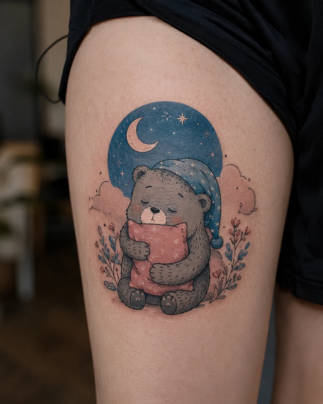Grey bear in a nightcap hugging a pink pillow against a night disc with a crescent and stars, on a thigh